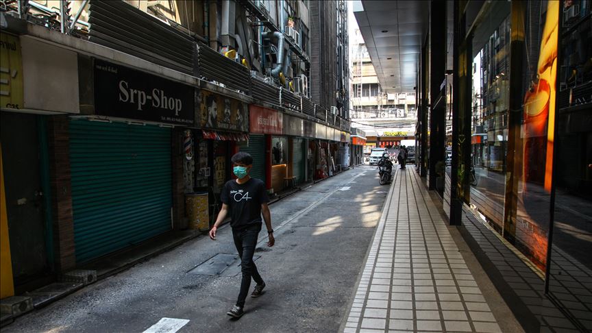 Man wearing face mask walking down an alley of closed shops